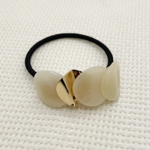 Detail of high-elasticity hair tie with cream resin petals and gold triangle charms