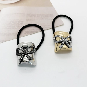 Eleganti elastici per capelli con fiocco di strass dorati e argentei su sfondo bianco