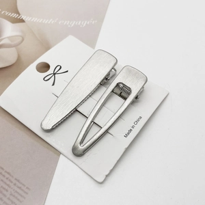 Detail of matte silver brushed metal hair clips in drop and geometric triangle shapes