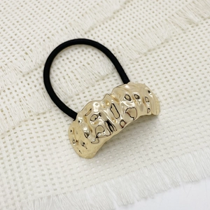 Detail of elegant gold hammered alloy buckle on black elastic ponytail holder