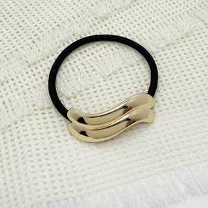 Detailed view of dual-layer golden wavy metal alloy pieces on a black elastic hair tie