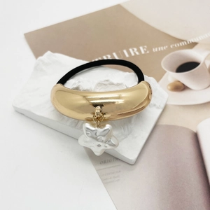 Détail d'un élastique à cheveux doré avec un pendentif étoile blanc effet perle