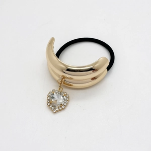 Detail of black elastic hair tie with polished gold C-shape charm and crystal heart pendant