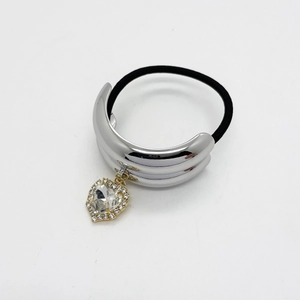 Detail of silver polished metal ponytail cuff with a large heart rhinestone pendant