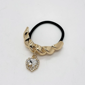 Detailed shot of golden twist metal hair ring with sparkling crystal heart charm
