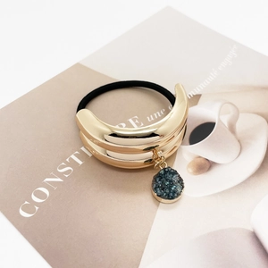Detailed macro view of U-shaped golden alloy hair tie with a dark green crystal pendant