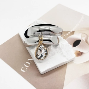 Detail of silver U-shaped ponytail holder with water drop crystal on white stone