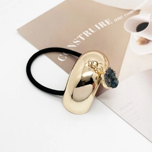 Close-up of golden U-shaped metal hair cuff with blue crystal pendant on elastic tie
