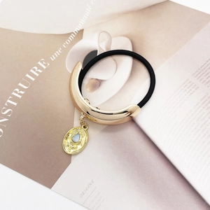 Detail of gold U-shaped hair tie with light blue stone pendant on fashion magazine