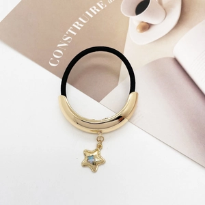 Detail of black elastic hair tie with golden star pendant and metallic gold buckle