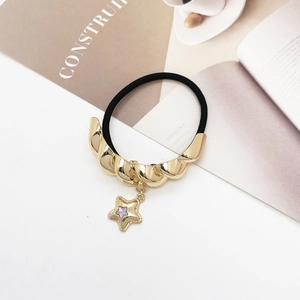 Close-up of black elastic hair tie with golden twisted metal and a star charm