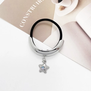 Detail of elastic hair tie with silver metallic arc and gradient star charm on a desk