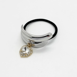 Detail shot of a silver ponytail cuff with a crystal heart pendant on a black hair tie