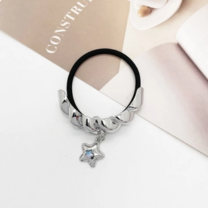 Close-up of elastic hair tie featuring silver twisted metal and star charm with glitter