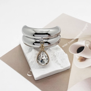 Detailed macro view of silver U-shaped hair ring with a clear teardrop crystal charm