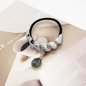 Detail view of elastic hair tie with silver alloy tube and green crystal pendant