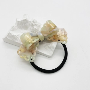 Detail of handmade acetate bow hair tie with marble texture on minimalist stone display