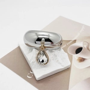 Macro view of silver U-shaped metal ring with a multifaceted water drop crystal pendant