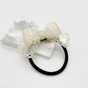 Detailed macro view of cream acetate bow hair tie with pearlescent finish and lace edges