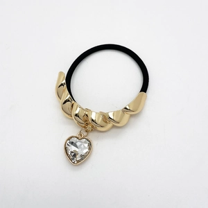 Close-up of alloy U-shaped ponytail holder with twisted gold metal and heart crystal charm