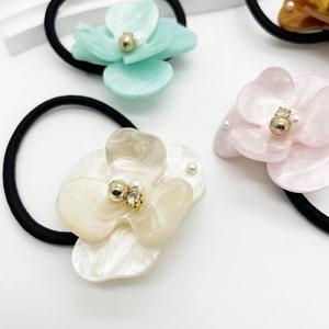 Close-up of acetate flower hair ties with pearl and rhinestone centers in pastel colors