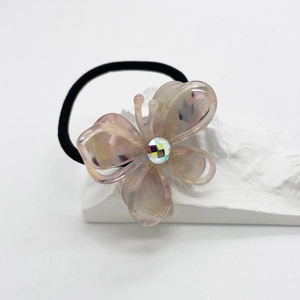 Detailed close-up of marble pattern butterfly hair tie with faceted crystal on stone pedestal