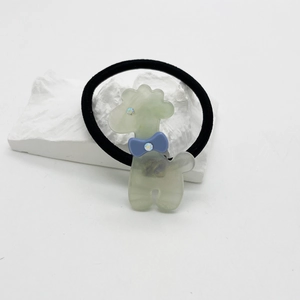Détail d'un pendentif caniche vert en acétate avec strass sur un élastique noir