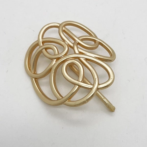 Detailed view of golden matte geometric intertwined metal hair hook with clover design