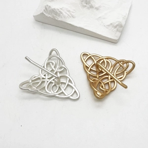 Close-up of gold and silver alloy ponytail hair clips with vintage Celtic knot triangle design