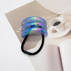 Chic U-shaped iridescent hair tie with multi-colored metallic gradient finish on magazine