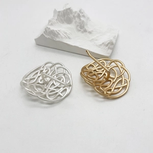 Detailansicht minimalistischer Haarklammern in Gold und Silber auf dekorativem Hintergrund