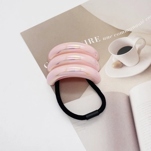 Detailed macro view of pink pearlescent resin hair tie with a stylish pleated texture