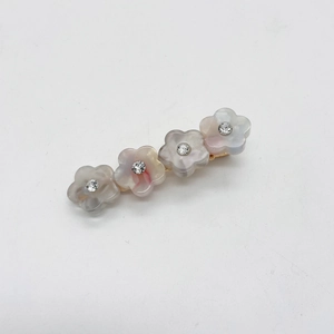 Détail de quatre barrettes à fleurs en résine avec strass et base en métal doré