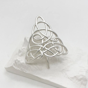 Macro detail of silver alloy Celtic knot hair clip on a minimalist textured stone background