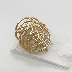 Detailansicht einer mattgoldenen geometrischen Haarklammer auf weißer Steindekoration