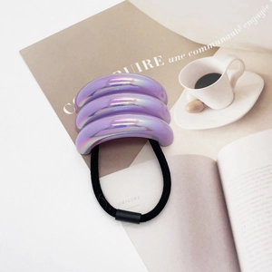 Detail of laser purple U-shaped resin hair tie on magazine with white coffee cup
