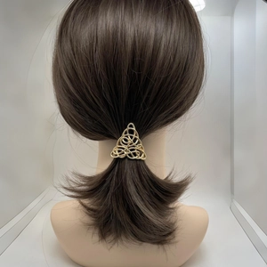 Close-up of golden alloy Celtic knot hair clip in a triangular design on a ponytail