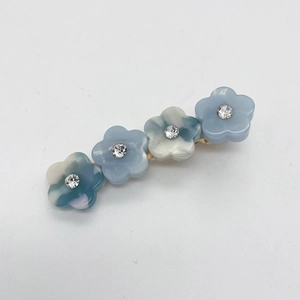 Détail de la pince à cheveux avec fleurs en résine bleue, strass et base dorée