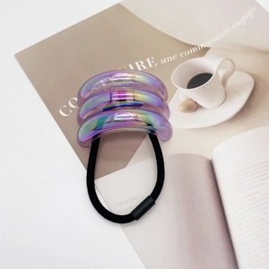 Detailed view of U-shaped laser iridescent charms on black elastic hair tie bands
