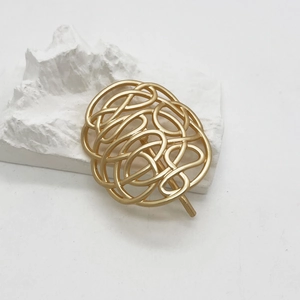 Nahaufnahme der abstrakten verflochtenen Haarspange aus Gold mit matter Oberfläche