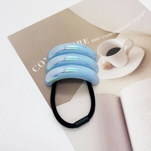 Macro detail of a colorful iridescent blue U-shaped hair tie on a magazine background