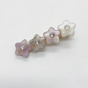 Détail de barrettes étoiles en acétate coloré et strass brillants sur monture dorée