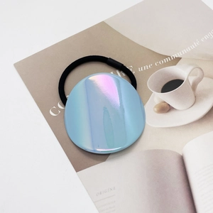 Close-up of iridescent light blue round hair tie on a minimalist French magazine
