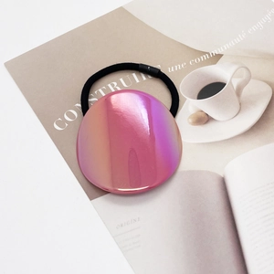 Close-up of holographic oval buckle on premium elastic hair tie over a magazine