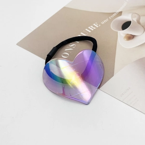 Vue détaillée d'un chouchou cœur violet iridescent avec élastique noir sur un magazine