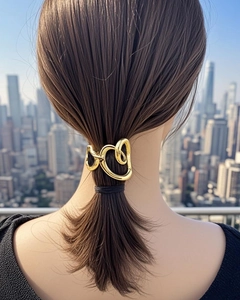 Detail of a minimalist gold alloy heart-shaped hair clip worn on a low ponytail