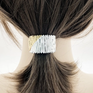Detail of two-tone gold and silver ponytail clip with vertical striped metal texture