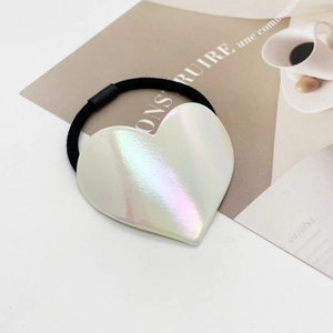 Détail de l'élastique à cheveux avec cœur holographique sur fond de magazine français