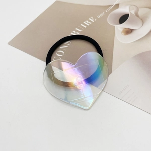 Gros plan d'un élastique à cheveux avec pendentif cœur irisé sur papier artistique