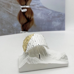 Close-up of pleated mixed-metal hair clip showing gold and silver textured finish